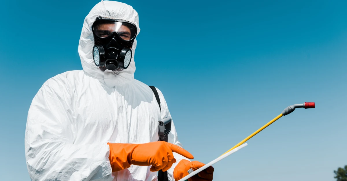 Pest control technician in protective suit and gas mask spraying outdoors under a clear blue sky, ideal for a Pest Control Facebook Ad.