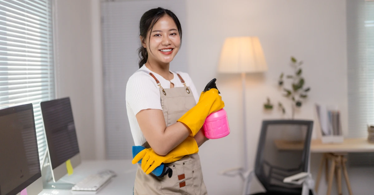 Smiling cleaning company employee holding cleaning products